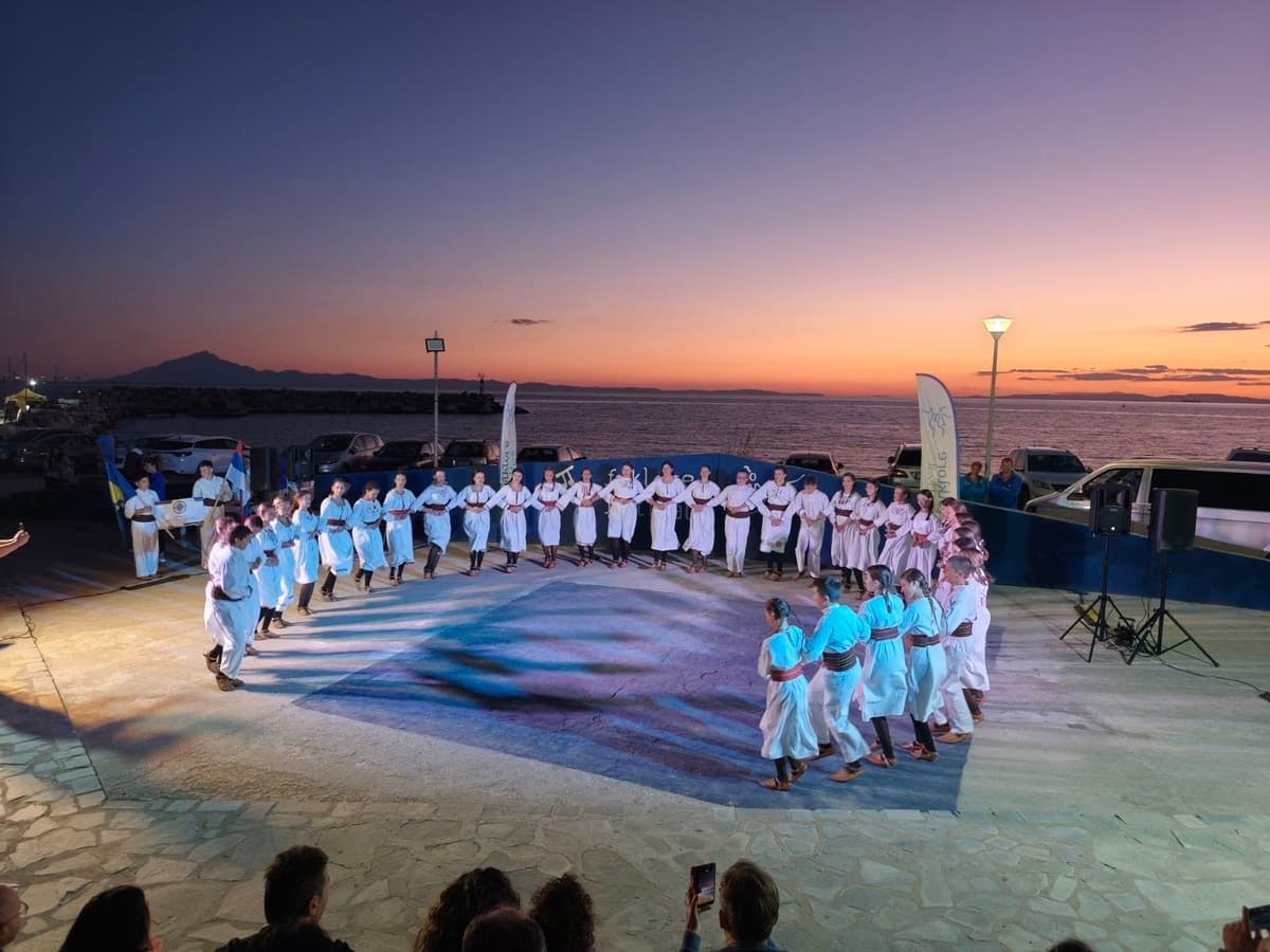 Članovi Udruženja igraju kolo na festivalskoj bini uz more, u zalazak sunca